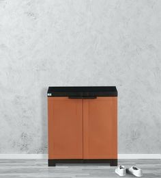 an orange cabinet sitting in front of a white wall with two shoes on the floor