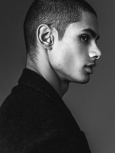 a black and white photo of a young man with ear piercings on his ears