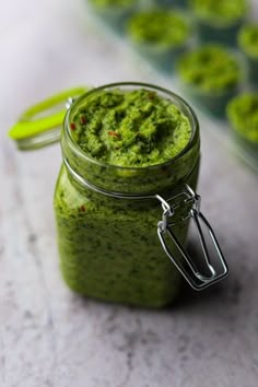 a jar filled with green pesto sitting on top of a table