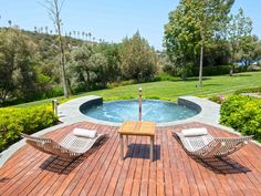 a wooden deck with two chairs next to a swimming pool