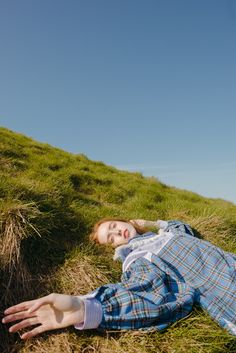 a woman laying in the grass on top of a hill