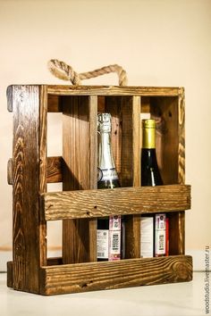 a wooden box with bottles in it sitting on a table next to a vase and bottle opener