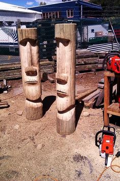 two wooden totems sitting on top of a dirt ground