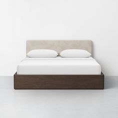 a bed with two pillows on top of it next to a white wall and floor