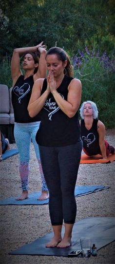 two women are doing yoga outside on the ground with their hands together in front of them