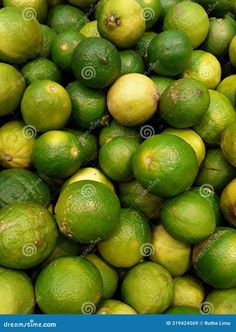 a pile of limes with green leaves and yellow ones in the background stock photo - image