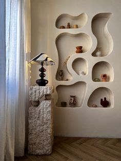 a white shelf sitting next to a lamp on top of a wooden floor