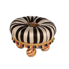 a black and white striped poufce with tassels sits on an ottoman