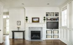 a living room filled with furniture and a fire place in front of a tv mounted on a wall