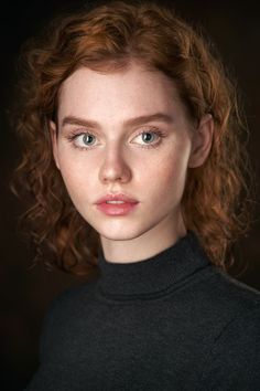 a woman with red hair and blue eyes is looking at the camera while wearing a turtle neck sweater