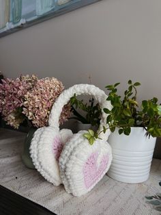 two crocheted headphones sitting on top of a table next to some potted plants