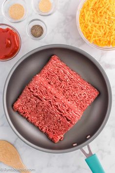 raw ground beef in a frying pan surrounded by ingredients to make an appetizer