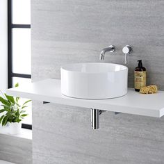 a white sink sitting on top of a counter next to a potted green plant