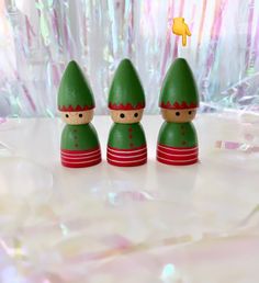 three green wooden toy figures sitting on top of a table