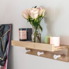 a vase with flowers and candles on a wooden shelf next to a wall mounted candle holder