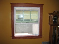 a window in a yellow room with a clock on the wall and a grandfather clock behind it