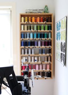 a sewing machine sitting in front of a shelf filled with spools of thread