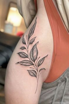 a black and white photo of a woman's back shoulder with leaves on it