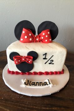 a birthday cake decorated with minnie mouse ears and red bow ties on a wooden table