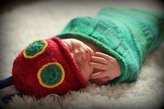 a newborn baby wearing a green and red knitted hat