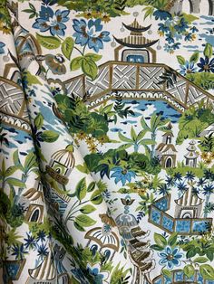 a close up view of a blue and green flowered fabric with a bridge in the background