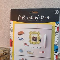 a refrigerator with stickers on it sitting in front of a wall