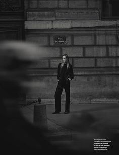 a man standing in front of a building with his hand on his hip and looking at the ground