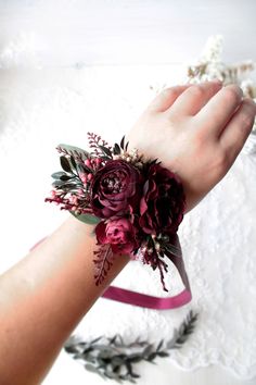 a woman's wrist with flowers and leaves on it, in front of a white background