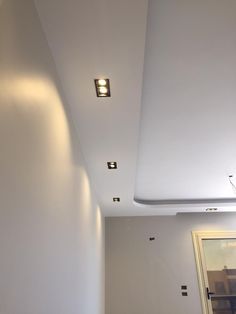 an empty room with white walls and recessed lighting on the ceiling is seen in this image