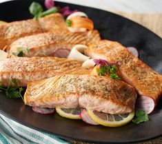 some fish and vegetables on a black plate