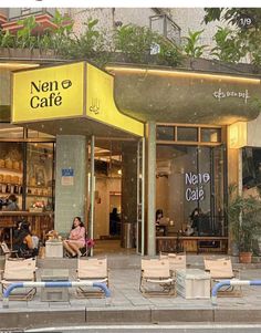 people are sitting on chairs in front of a cafe