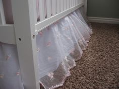 a white crib with pink flowers on the bottom and ruffles at the bottom