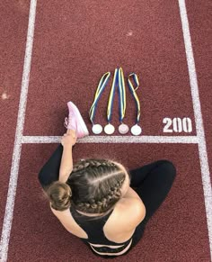 a woman sitting on top of a red tennis court next to a pair of shoes