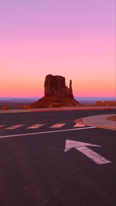 an arrow painted on the road in front of a rock outcropping at sunset