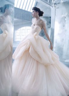 a woman in a wedding dress is walking down the runway