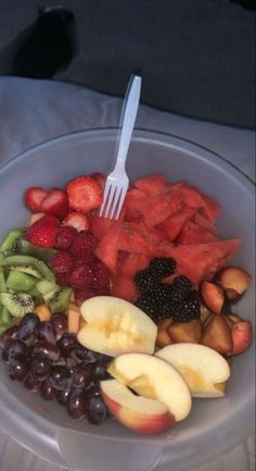 a bowl filled with lots of different types of fruit and a fork sticking out of it