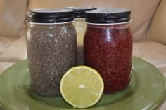 two jars filled with different kinds of food on top of a green plate next to a slice of lemon