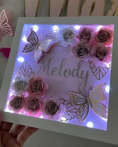 someone is holding up a card with flowers and butterflies on it that says melody in the center