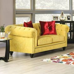 a living room with yellow couches and red pillows on the back of each sofa