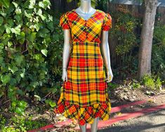 "Just about thee cutest little number you ever did see! Adorable 1970s primary colored plaid midi dress by Petiteen! Lightweight synthetic fabric in a bold primary colored plaid print, bobble button closures from chest to waist, ruffled hem, nylon back zip closure, and the sweetest puffed sleeves! Excellent vintage condition with no noted flaws or defects (zipper's fully functional, just a smidge snug on the mannequin).  Best fits an XS. See measurements for exact fit.  APPROXIMATE FLAT MEASUREMENTS Shoulder: 14\" Sleeve: 8.5\" Chest: 16.5\" Waist: 12.5\" Hip: 21\" Length: 45\"" Retro Short Sleeve Plaid Dress, Retro Plaid Mini Dress, Check Dress, Puffed Sleeves Dress, 50s Dresses, Printed Maxi, Dress Suits, Printed Maxi Dress, 70s Fashion