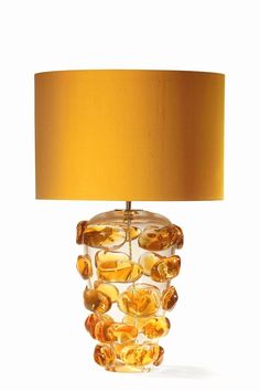 a glass lamp with a yellow shade on the base and a gold lampshade