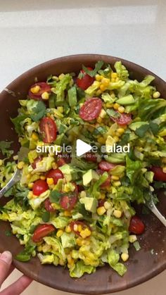 a salad with lettuce, tomatoes and corn in a brown bowl