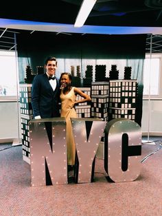 a man and woman posing in front of the new york city sign