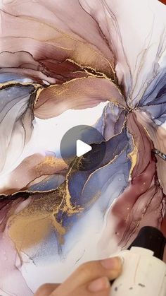 someone is painting an abstract flower with gold and purple paint