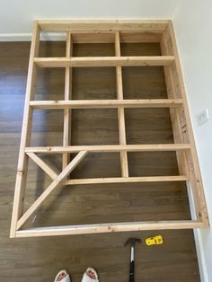 someone is standing on the floor with their feet up in front of an unfinished bed frame