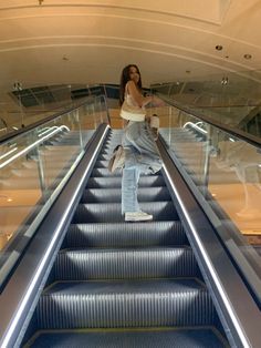 a woman is standing on an escalator with her arms in the air as she rides down it