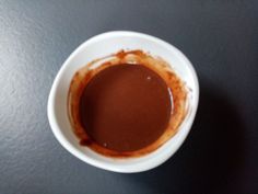 a white bowl filled with brown liquid on top of a table