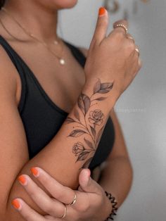 a woman holding her arm with a flower tattoo on it's left wrist and finger