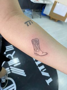 a small tattoo on the arm of a woman's left arm with a cowboy boot