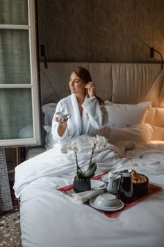 a woman sitting on a bed holding a cell phone